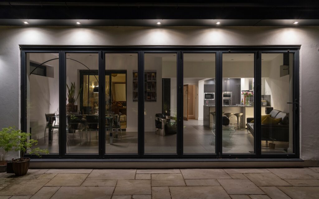 Cortizo Bifold Plus showing supply only aluminium doors at night with overhead lights